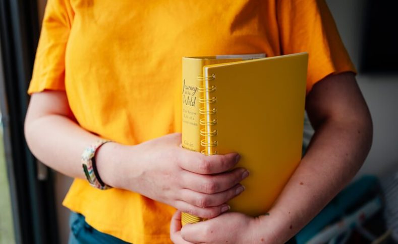 girl in yellow t-shirt holding yellow books virtual assistants